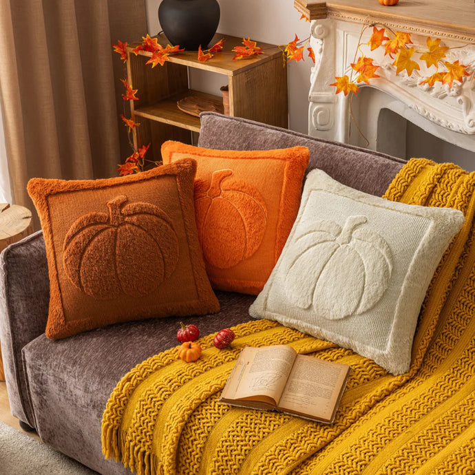 Cozy living room with a sofa adorned with pumpkin-themed pillows and a yellow blanket. The Velour Pumpkin Cushion Cover by Allthingscurated is a beautiful way to bring the warmth of fall into your home. With its elegant tufted pumpkin design and soft velour fabric, it offers both comfort and style. Perfect for autumn and Thanksgiving, this decorative pillow adds a cozy, inviting touch to any space.