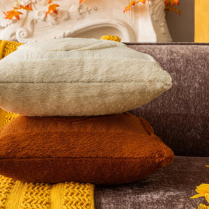 Stack of textured pillows in various colors on a sofa. Cozy living room with a sofa adorned with pumpkin-themed pillows and a yellow blanket. The Velour Pumpkin Cushion Cover by Allthingscurated is a beautiful way to bring the warmth of fall into your home. With its elegant tufted pumpkin design and soft velour fabric, it offers both comfort and style. Perfect for autumn and Thanksgiving, this decorative pillow adds a cozy, inviting touch to any space.