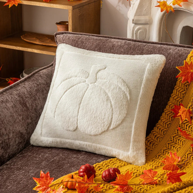 White pillow with pumpkin design on a brown couch with autumn decorations. Cozy living room with a sofa adorned with pumpkin-themed pillows and a yellow blanket. The Velour Pumpkin Cushion Cover by Allthingscurated is a beautiful way to bring the warmth of fall into your home. With its elegant tufted pumpkin design and soft velour fabric, it offers both comfort and style. Perfect for autumn and Thanksgiving, this decorative pillow adds a cozy, inviting touch to any space.
