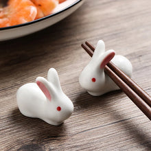 Load image into Gallery viewer, Enhance your Asian dining experience with our Ceramic Rabbit Chopstick Rests by Allthingscurated. These pieces will bring a playful edge to your table with their ability to keep your chopsticks clean and secure. Comes in a set of 3 or 6 pieces.
