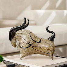 Load image into Gallery viewer, Decorative glass bull sculpture on a table with a blurred background. Rex Decorative Bull by Allthingscurated are meticulously handmade from high quality glass. Comes in three striking finishes—an all-all black edition or two-tone variants featuring bold graphic elements. Rex brings contemporary flair and bold energy to any room. More than décor, it’s an ideal gift for those born under the Ox zodiac and Taurus sign.
