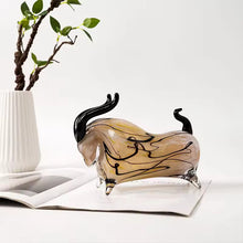 Load image into Gallery viewer, Glass bull figurine on an open book with a plant in the background. Rex Decorative Bull by Allthingscurated are meticulously handmade from high quality glass. Comes in three striking finishes—an all-all black edition or two-tone variants featuring bold graphic elements. Rex brings contemporary flair and bold energy to any room. More than décor, it’s an ideal gift for those born under the Ox zodiac and Taurus sign.

