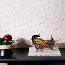 Load image into Gallery viewer, Decorative glass bull sculpture on a book with a white textured wall background. Decorative bull sculptures on books with a candle against a textured white wall. Rex Decorative Bull by Allthingscurated are meticulously handmade from high quality glass. Comes in three striking finishes—an all-all black edition or two-tone variants featuring bold graphic elements. Rex brings contemporary flair and bold energy to any room. More than décor, it’s an ideal gift for those born under the Ox zodiac and Taurus sign.

