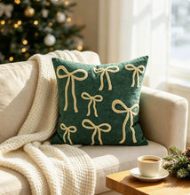 Load image into Gallery viewer, A dark green square throw pillow with an embroidered pattern of cream-colored bows on a sofa, adding a playful touch to home decor.
