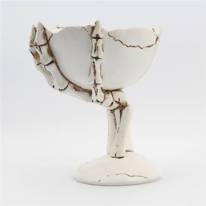 Gothic Skeleton Hand Storage Bowl by Allthingscurated  boasts a spooky design featuring a ghoulish skeleton claw in neutral warm off-white and vivid hand bones encircling the bowl. Perfect for adding a frightful touch to your Halloween decor. Crafted from resin and measuring height of 13.5m or5.3 inches and width of 12cm or 4.7 inches.