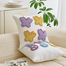 Load image into Gallery viewer, Decorative pillow with butterfly and bunny designs on a couch. Spring Melody Embroidered Cushion Covers by Allthingscurated feature charming seasonal details to transition your home into Spring and Easter effortlessly. Each cover showcases meticulous embroidery to add depth and visual interest to your sofa and furniture.
