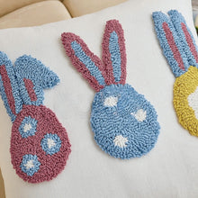 Load image into Gallery viewer, Three knitted bunny in blue, pink, and yellow on the white cushion cover surface. Spring Melody Embroidered Cushion Covers by Allthingscurated feature charming seasonal details to transition your home into Spring and Easter effortlessly. Each cover showcases meticulous embroidery to add depth and visual interest to your sofa and furniture.
