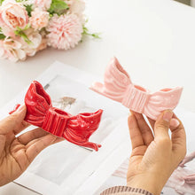 Load image into Gallery viewer, Two decorative bow candle holders one red and one pink, held by hands on a light surface with flowers in the background. Fashion Bow Candle Holder by Allthingscurated spots a distinctive knot design, beautiful yet practical. Perfect for wedding celebrations, home styling, or to infuse warmth and romance into any living space. Available in three colors and 2 sizes.
