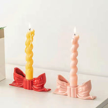 Load image into Gallery viewer, Two twisted candles in red and pink bow candle holders on a white surface. Fashion Bow Candle Holder by Allthingscurated spots a distinctive knot design, beautiful yet practical. Perfect for wedding celebrations, home styling, or to infuse warmth and romance into any living space. Available in three colors and 2 sizes.

