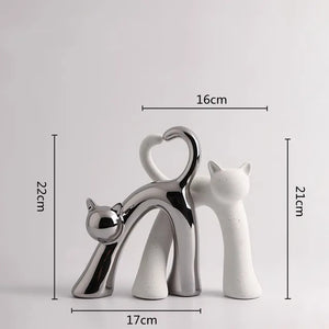 These Cat Couple Love Figurines by Allthingscurated are perfect for cat lovers. Made of ceramic, they feature a pair of cute and whimsical cats in contrasting colors, with their tails entwined to form a heart shape. A romantic and unique gift for any occasion.  This set features a pair of silver and white cats.