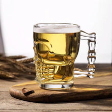 Load image into Gallery viewer, Skull Beer Mug by Allthingscurated blends functionality with style. Made with thickened glass with a heavy bottom for stability, it spots a fun, cool skull shape design that is ideal for Halloween or everyday use. The large capacity is perfect for beer or any beverage. Add this must-have mug to your drinkware collection and be ready for any gatherings or house parties.
