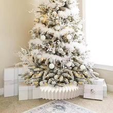 Load image into Gallery viewer, Decorated Christmas tree with white ornaments, lights and paper collar, surrounded by presents in a room. Transform your holiday setup with the striking Honeycomb Christmas Tree Collar by Allthingscurated. Crafted from premium paper with easy setup, its distinctive pleated design delivers sophisticated visual interest while concealing the tree base with understated elegance. The crips white finish works beautifully with any tree style.
