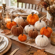Load image into Gallery viewer, A styled autumn table setting featuring a collection of velvet pumpkins in orange, rust brown, and cream white, arranged on a linen runner with fall leaves, candles, and plates.

