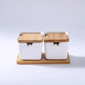 Ceramic Seasoning Storage Jars by Allthingscurated are the perfect storage solution to keep your herbs, seasonings and spices. Made of durable ceramic with a sustainable bamboo flip lid for easy access during cooking. These jars are not only functional but also environmentally friendly. Comes with a bamboo tray and ceramic spoons. Featured here is a set of 2 white jars with spoons and tray.