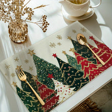 Load image into Gallery viewer, Christmas-themed placemats with trees and gold cutlery on a table.
