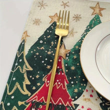 Load image into Gallery viewer, Gold fork on a Christmas-themed placemat with trees and stars
