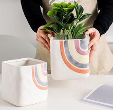 Load image into Gallery viewer, Biba Ceramic Square Planter by Allthingscurated features hand-painted rainbow-like pattern on a creamy white background with a groovy and hippie vibe. Available in small, medium and large size. Small pot measures 11.5cm by 11.5cm or 4.5 inches by 4.5 inches. The medium pot measures 11.8cm by 11.8cm or 4.6 inches by 4.6 inches. The large pot measures 14cm by 14cm or 5.5 inches by 5.5 inches.
