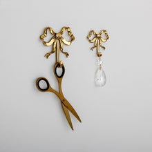 Load image into Gallery viewer, These pretty wall hooks by Allthingscurated are made of high-quality brass with a vintage gold finish.  Fashioned like a bow tied with ribbon, it’s feminine and perfect for the walk-in wardrobe or powder room. Comes in small and large size. Small hook measures 7.3cm or 2.8 inches in height and 6.5cm or 2.5 inches in width. Large hook measures 10.3cm or 4 inches in height and 9.5cm or 3.7 inches in width. Sold as individual hooks or a set of small and large hooks.
