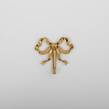 Load image into Gallery viewer, These pretty wall hooks by Allthingscurated are made of high-quality brass with a vintage gold finish.  Fashioned like a bow tied with ribbon, it’s feminine and perfect for the walk-in wardrobe or powder room. Comes in small and large size. Small hook measures 7.3cm or 2.8 inches in height and 6.5cm or 2.5 inches in width. Large hook measures 10.3cm or 4 inches in height and 9.5cm or 3.7 inches in width. Sold as individual hooks or a set of small and large hooks. This is a small hook.
