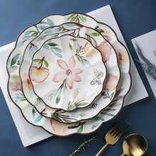 Load image into Gallery viewer, Allthingscurated’s Camille dinnerware features hand-painted florals, fauna and pretty butterflies and a color scheme of pink, yellow, blue,green and brown against a white ceramic background. Every plate is designed with a brown-lined scallop edge. Available in 6, 8 and 10 inches or 15.5, 20 and 25.5cm.
