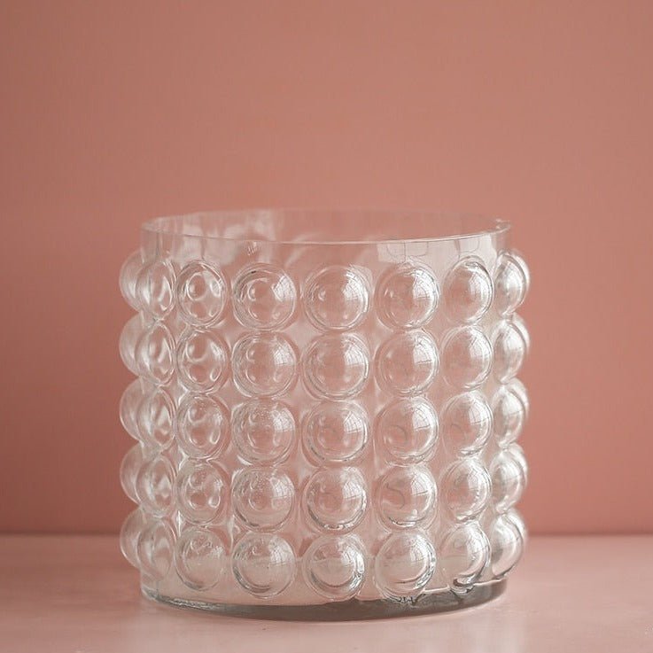 Zayla Bubble Vase by Allthingscurated features a geometric bubble design. The eye-catching detail and design are enough to make it a statement centerpiece with or without floral display. Comes in black or clear and in 2 sizes. The short vase measures 17cm or 6.6 inches in height and 16cm or 6.2 inches in diameter.  The tall vase measures 27.5cm or 10.7 inches in height and 13cm or 5 inches in diameter. This is a pair of clear vases with small pink flowers in the tall vase. This is a short clear vase.