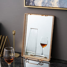 Load image into Gallery viewer, Donatella Mirror tray by Allthingscurated features a mirror surface and intricate gold-gilded pattern surround all sides of the rectangle tray and with 2 handles. Available in small, medium and large size. Featured here is a large rectangle tray leaning agains the wall. The surface of the tray can eve become a mirror on its own.

