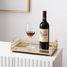 Load image into Gallery viewer, Donatella Mirror tray by Allthingscurated features a mirror surface and intricate gold-gilded pattern surround all sides of the rectangle tray and with 2 handles. Available in small, medium and large size. Featured here is a large tray with a bottle of red wind and a red wine glass.
