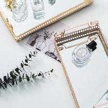 Load image into Gallery viewer, Donatella Mirror tray by Allthingscurated features a mirror surface and intricate gold-gilded pattern surround all sides of the rectangle tray and with 2 handles. Available in small, medium and large size. Featured here are two trays with perfume bottles.
