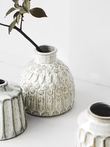 Kiara Stoneware Vases by Allthingscurated is a collection of small ceramic vases with a rustic beauty. Comes in various shapes and sizes with beautiful details and etched patterns. Off-white in color in 5 designs.