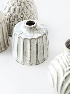 Kiara Stoneware Vases by Allthingscurated is a collection of small ceramic vases with a rustic beauty. Comes in various shapes and sizes with beautiful details and etched patterns. Off-white in color in 5 designs.