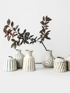 Kiara Stoneware Vases by Allthingscurated is a collection of small ceramic vases with a rustic beauty. Comes in various shapes and sizes with beautiful details and etched patterns. Off-white in color in 5 designs.