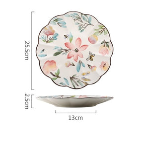Allthingscurated’s Camille dinnerware features hand-painted florals, fauna and pretty butterflies and a color scheme of pink, yellow, blue,green and brown against a white ceramic background. Every plate is designed with a brown-lined scallop edge. This plate is 10 inches or 25.5cm.