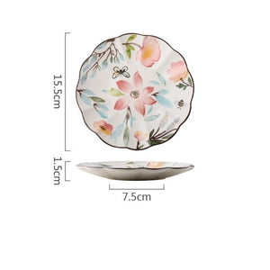 Allthingscurated’s Camille dinnerware features hand-painted florals, fauna and pretty butterflies and a color scheme of pink, yellow, blue,green and brown against a white ceramic background. Every plate is designed with a brown-lined scallop edge. This plate is 6 inches or 15.5cm.