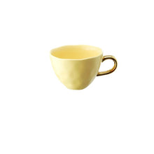 Load image into Gallery viewer, Allthingscurated glazed porcelain cup with gold handle in pastel yellow. Designed with a slight all-over concave effect surface that is unique. Has a capacity of 360ml or 12 ounce.
