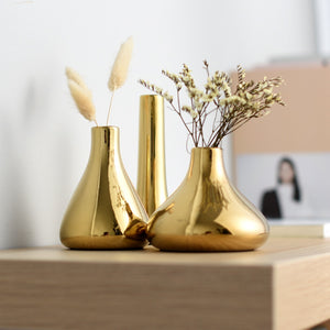 Gold ceramic mini vases in 3 designs nicely arranged on a table top.