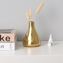 Load image into Gallery viewer, Solo gold mini vase between a stack of books and a mini ceramic tree.
