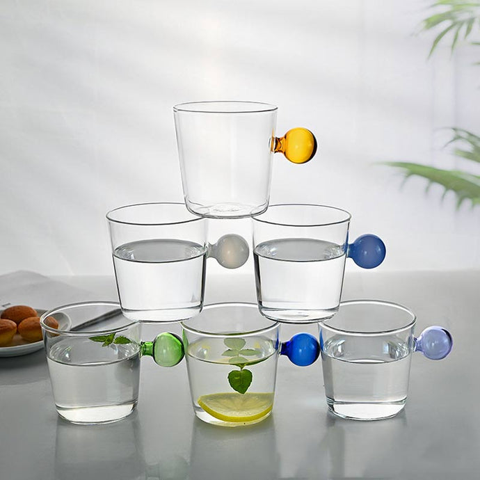Drinking Glass with colored spherical handle. measuring 8.5 x 8.5 x 7cm or 3.3 x 3.3 x 3 inches with a capacity of 350ml or 11.8 ounce. 